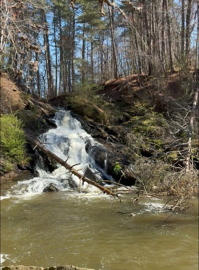 A small waterfall cascading down a rocky, forested hillside.